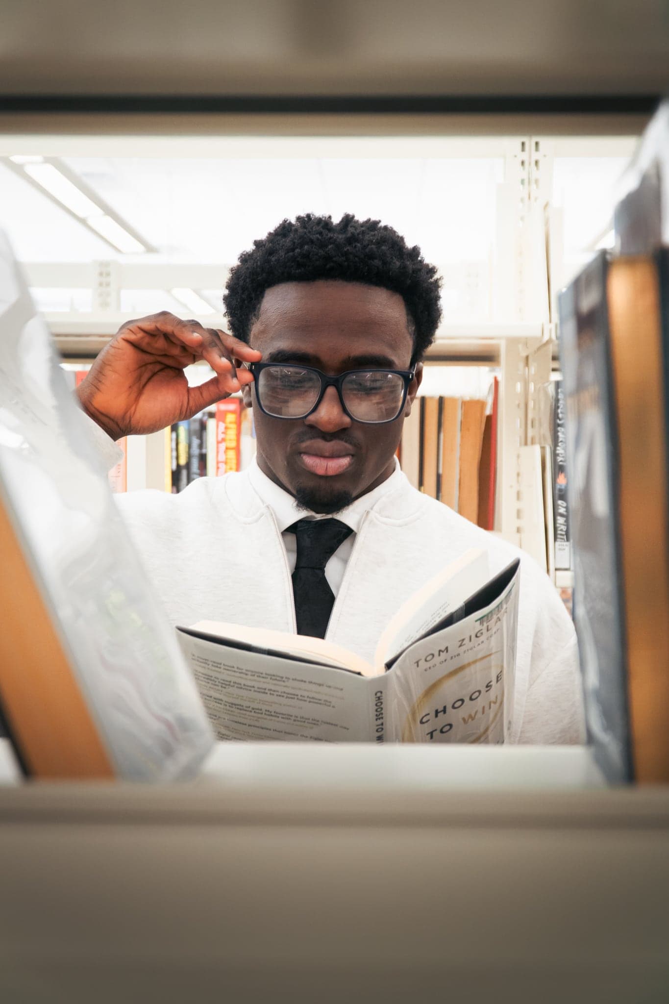 A portrait framed through shelving, caught mid-thought