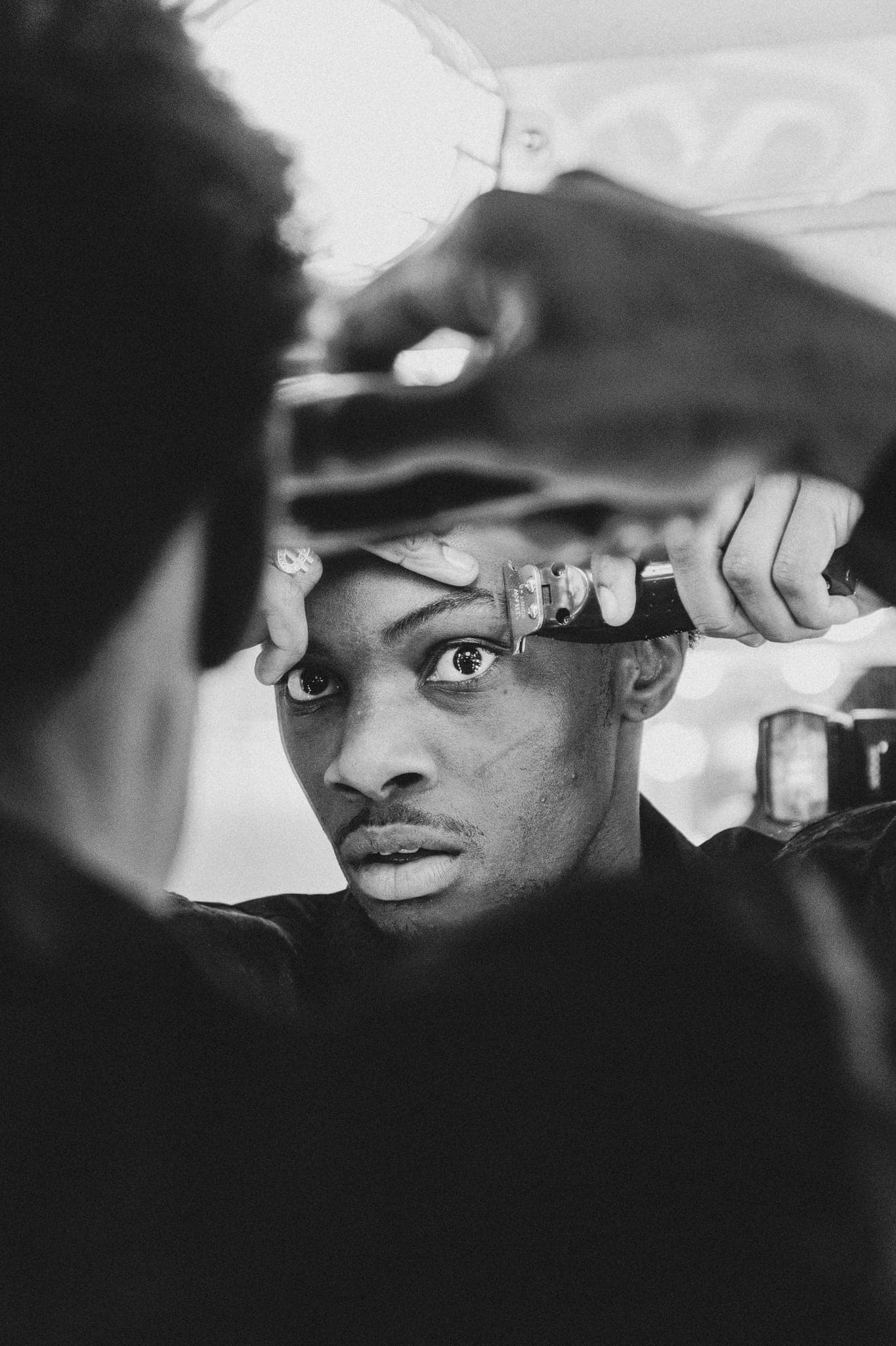 A close black-and-white portrait, hands framing the face