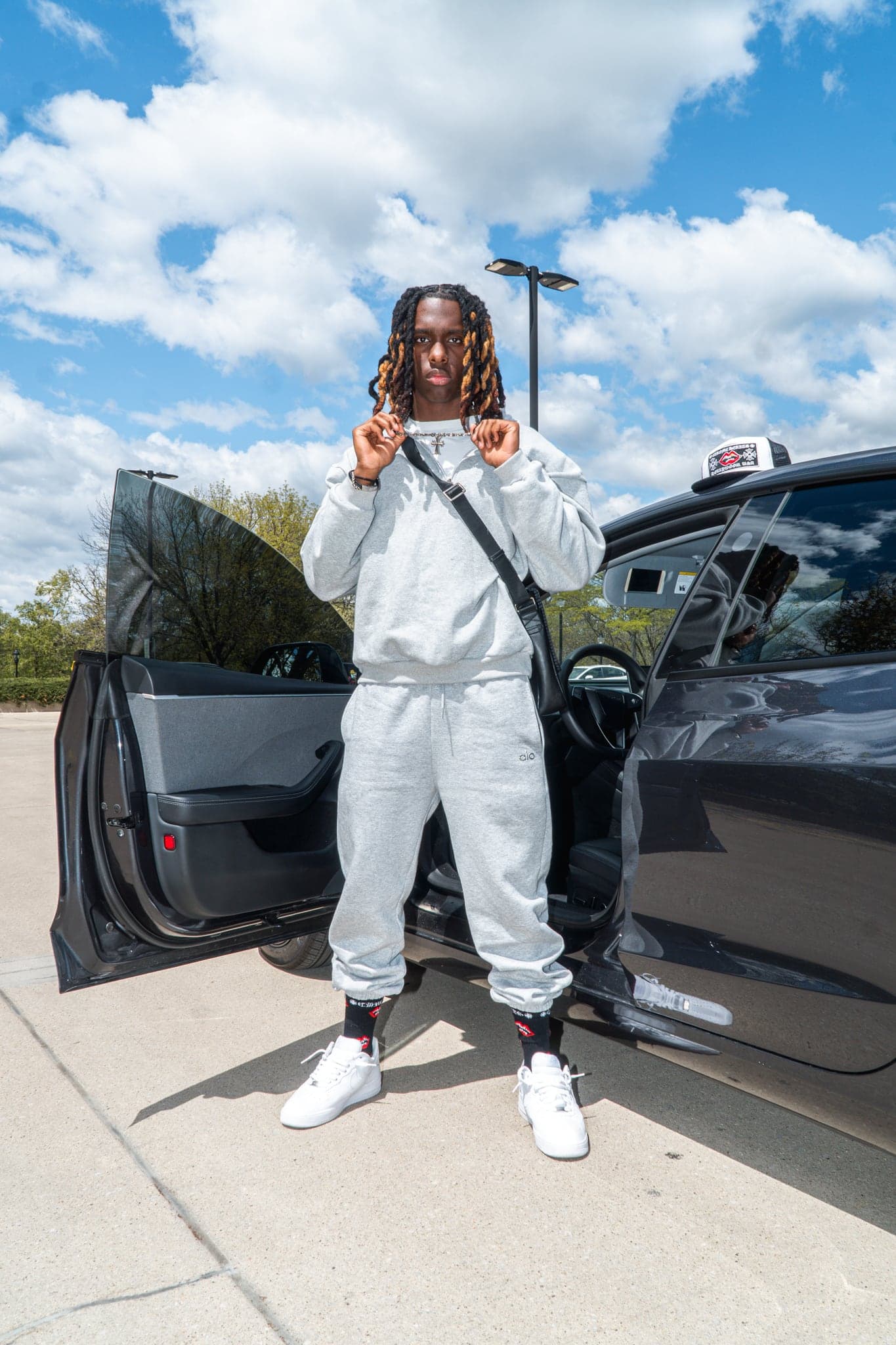 A full-length street portrait beside a parked car