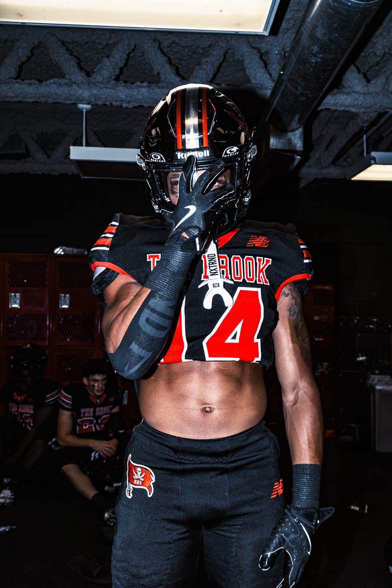 A football player in helmet and pads, lit against the dark