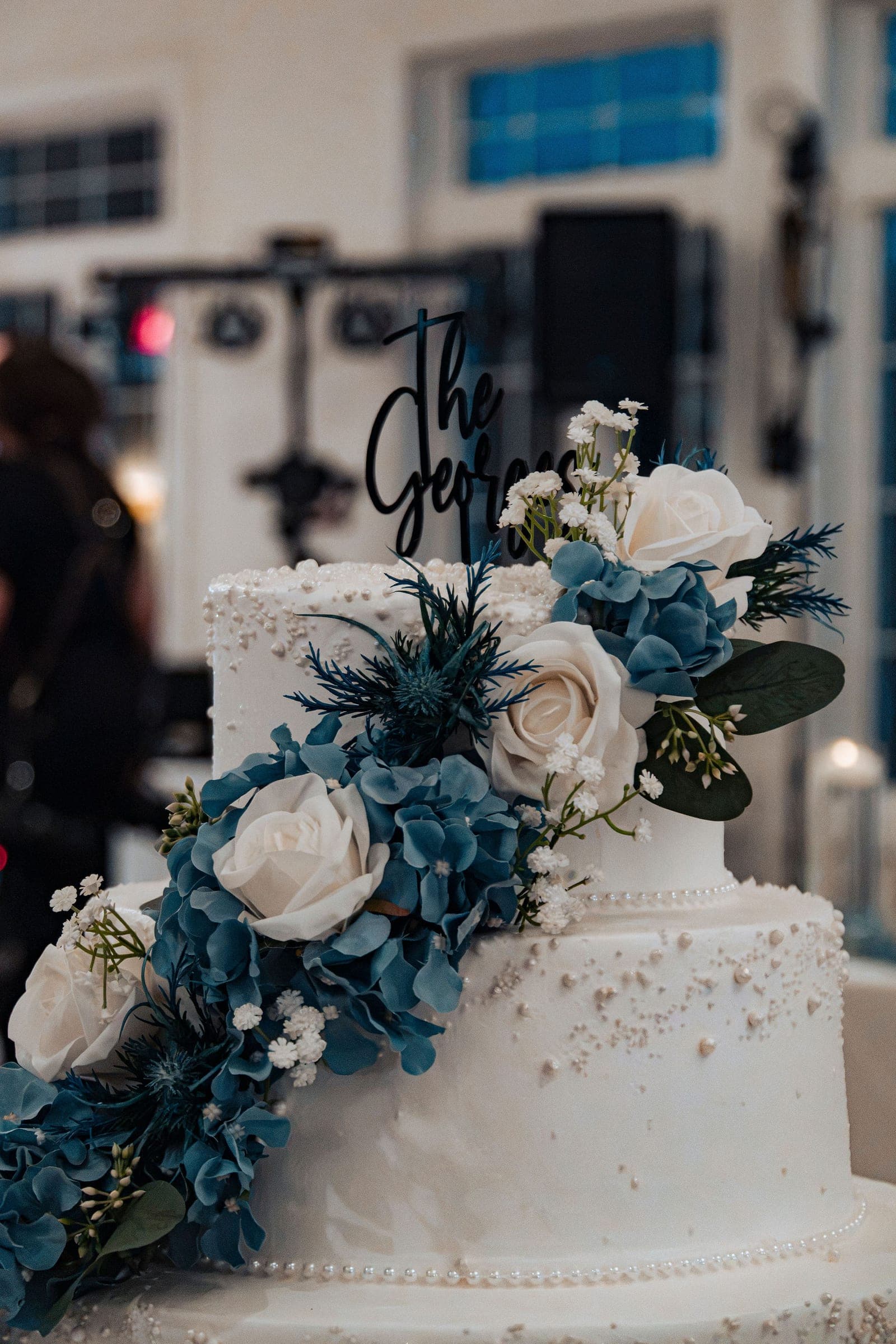 A tiered wedding cake dressed in dusty-blue florals