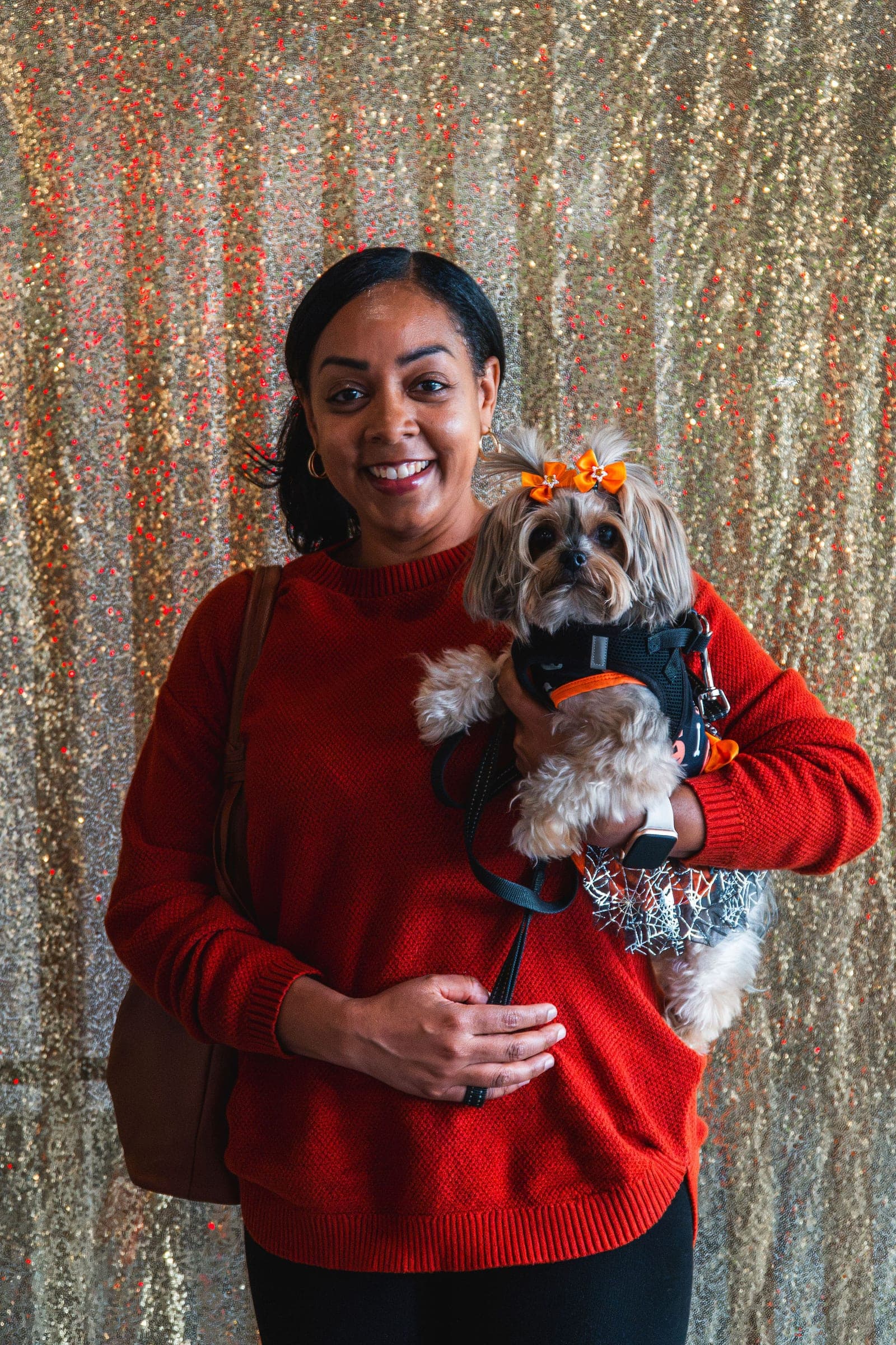A guest and her Yorkie against the gold sequin backdrop at the Windy City Yorkies meet-up