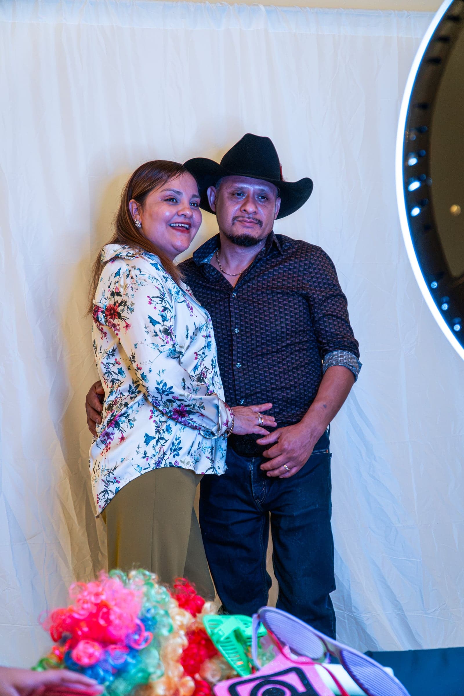 A couple photographed together against the party backdrop