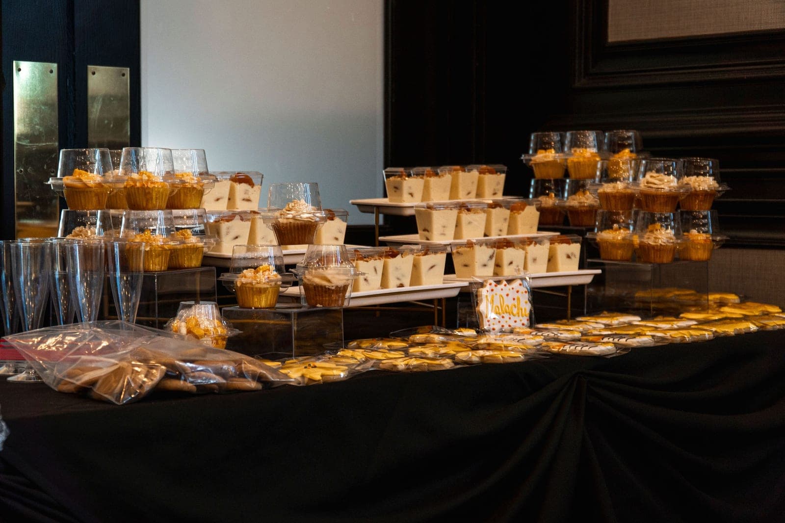 A dessert table of cupcakes, favors and gold-wrapped treats