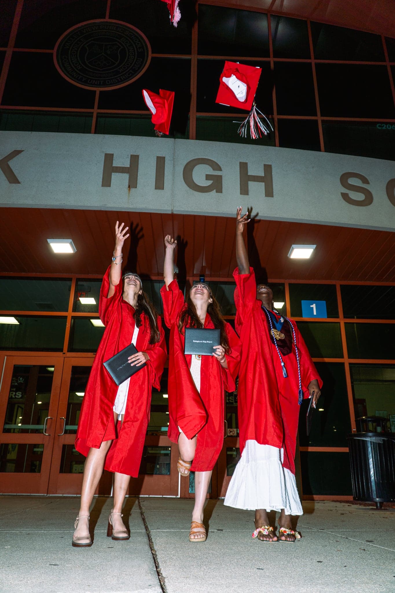 Graduates in cap and gown celebrating outside school