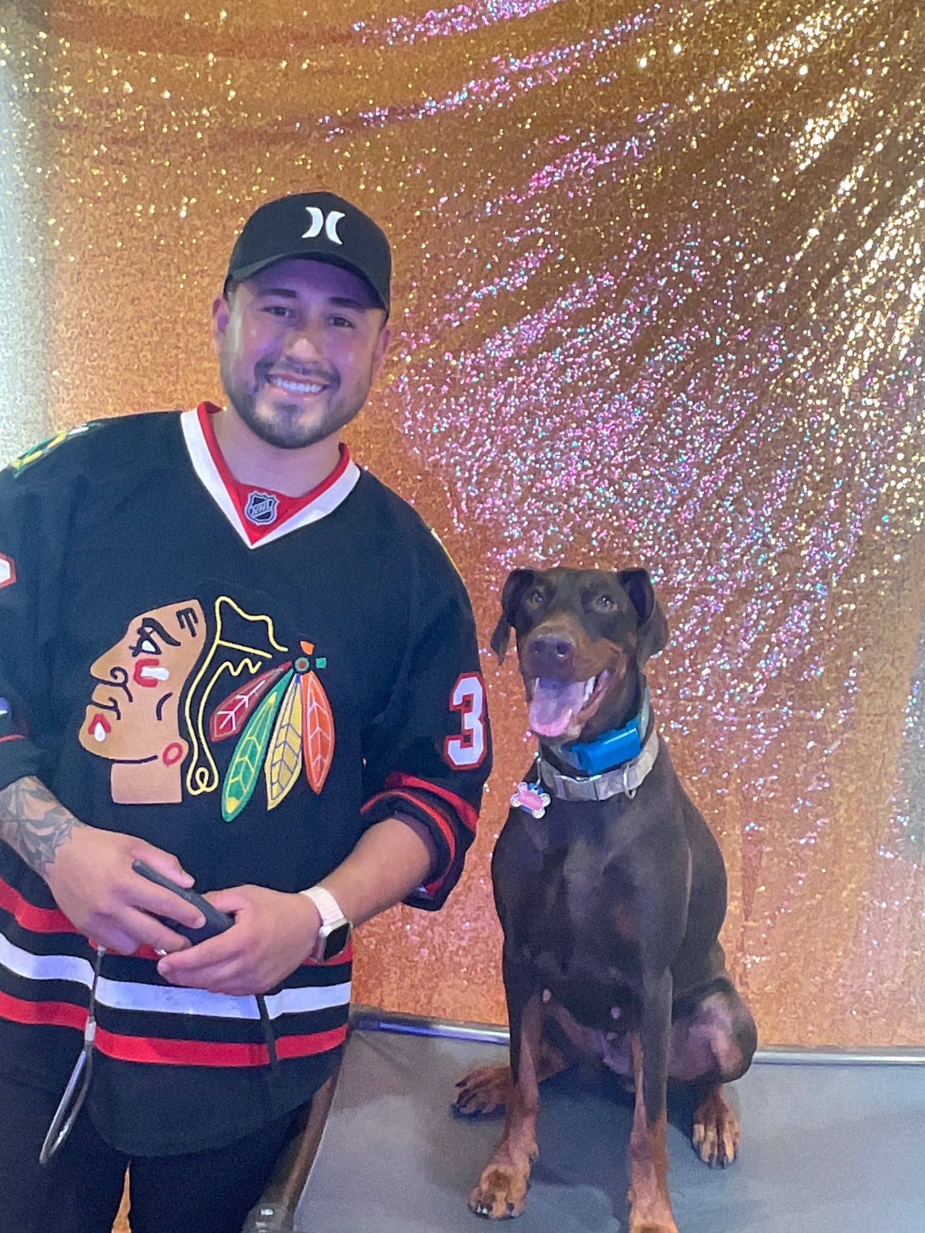 A guest and his dog at the booth against a gold sequin backdrop